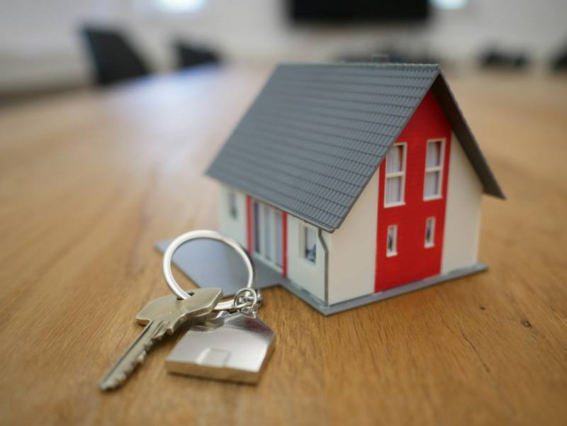 Llaves de casa sobre una mesa junto a una casita de modelo