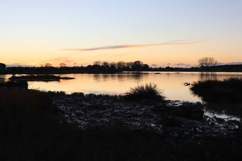 Atardecer sobre agua tranquila y humedales bajos, como el Delta cerca de Stockton