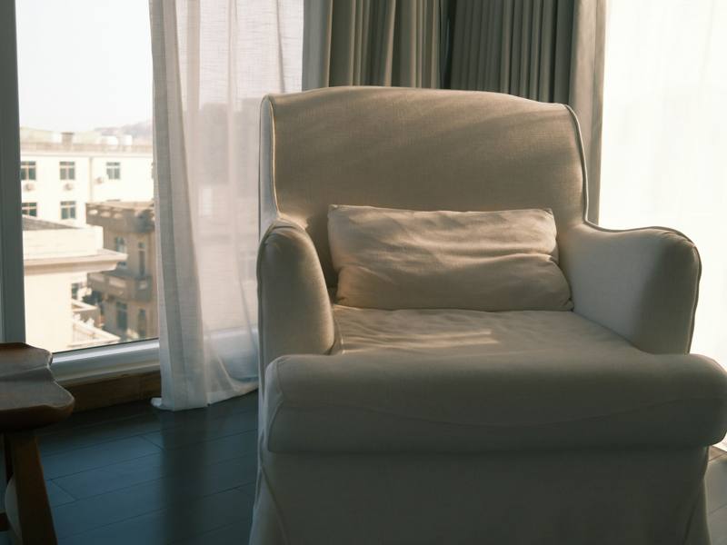 Un sillón blanco junto a una ventana soleada