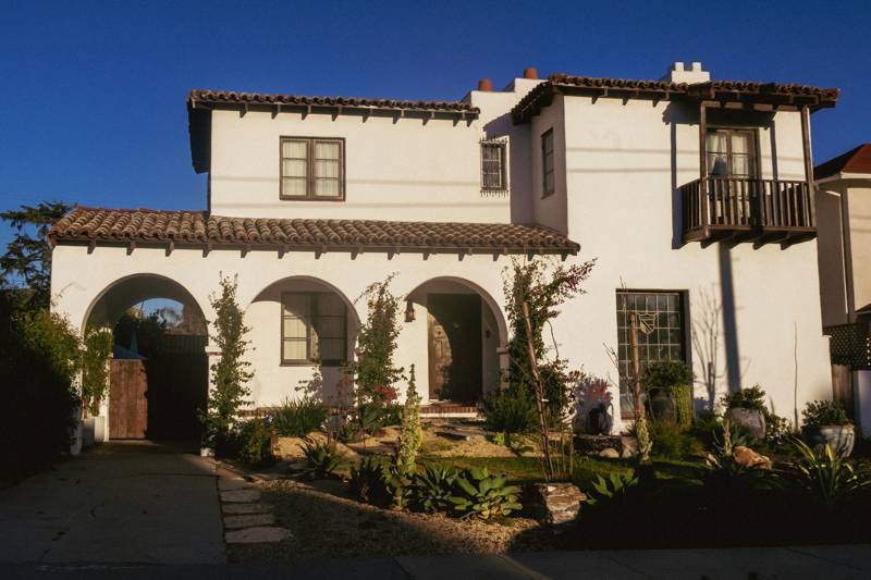 Casa blanca estilo español con entrada en arco y jardín de bajo consumo de agua